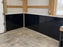 Pole barn interior corner with black HDPE wall liner installed along the base of metal walls
