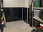 Garage storage corner with black HDPE wall liner behind metal shelving and storage bins
