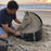 Sand sculptor using an HDPE plastic form ring to carve a horse head sand sculpture on the beach
