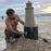 Sand sculptor using an HDPE plastic form to build a lighthouse sand sculpture on the beach
