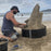 Sand sculptor using an HDPE plastic form ring to carve a shark sand sculpture on the beach
